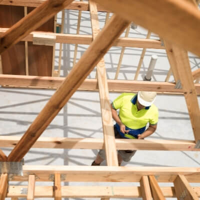 Looking down on a construction working standing in the middle of a wooden frame of a new building